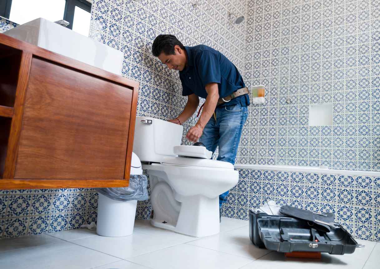 plumber fixing a toilet in the bathroom